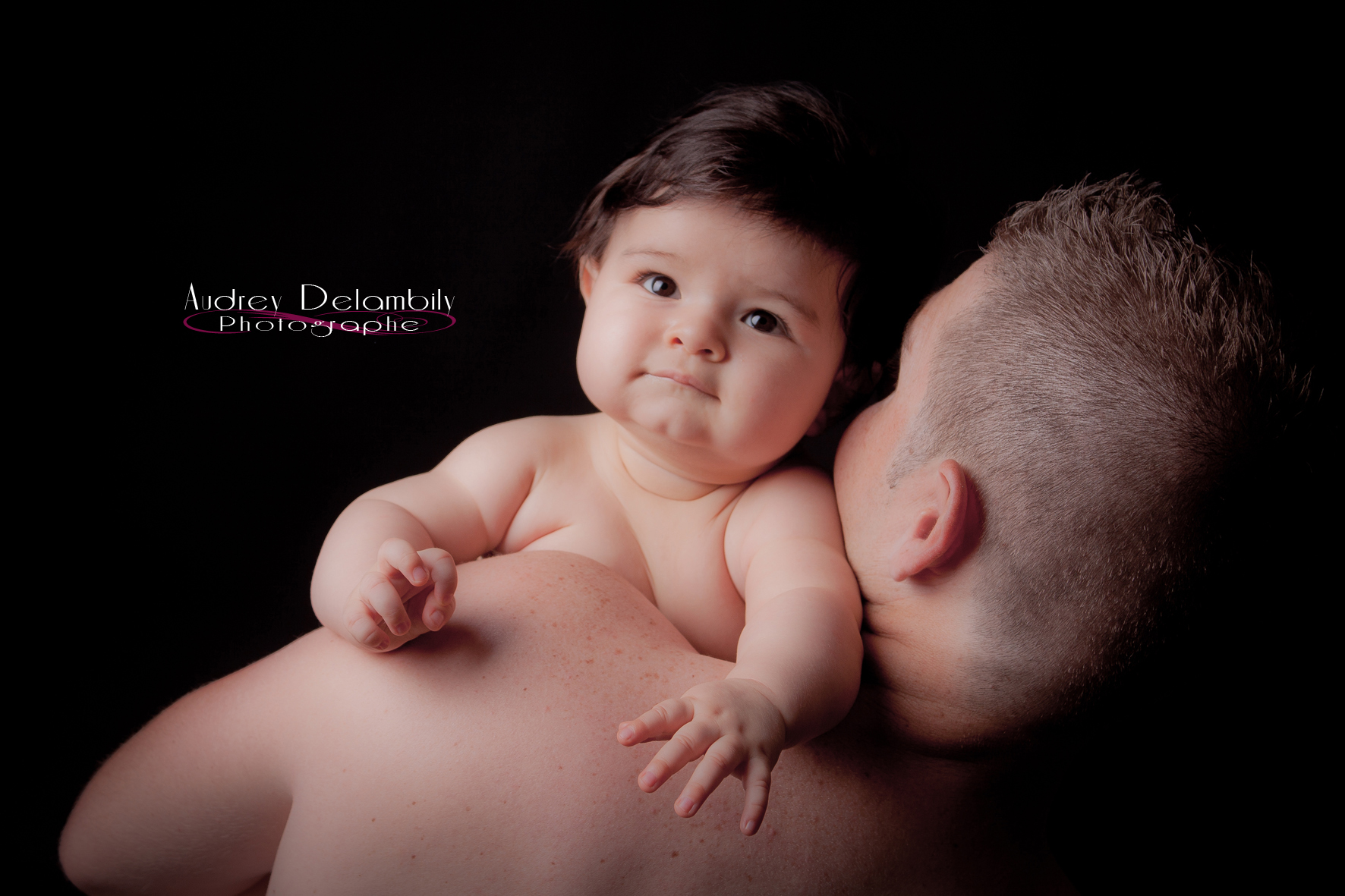 Photo prise en studio professionnel d'une petite fille dans les bras de son papa. 